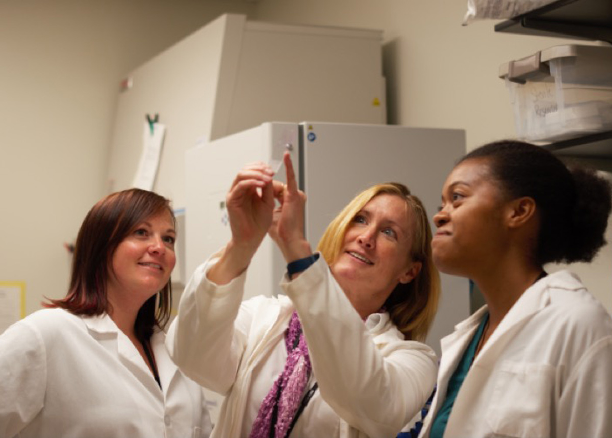 students and Professor Alison Bauer looking at a test tube
